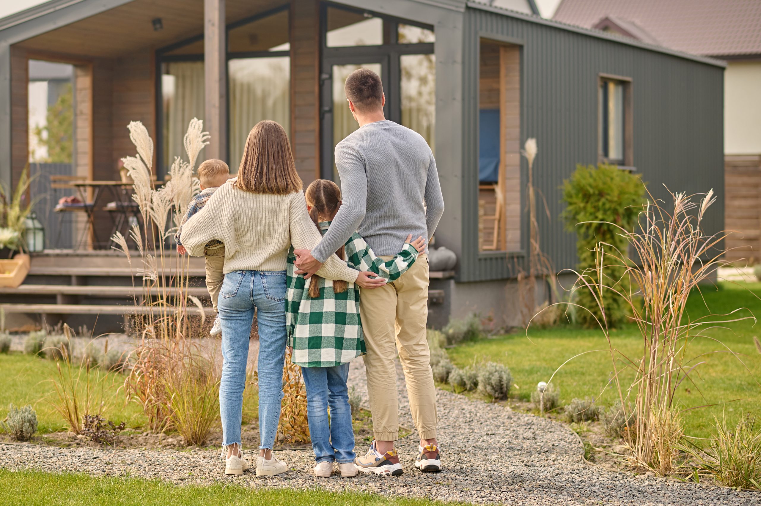 back-view-family-hugging-admiring-their-home-scaled