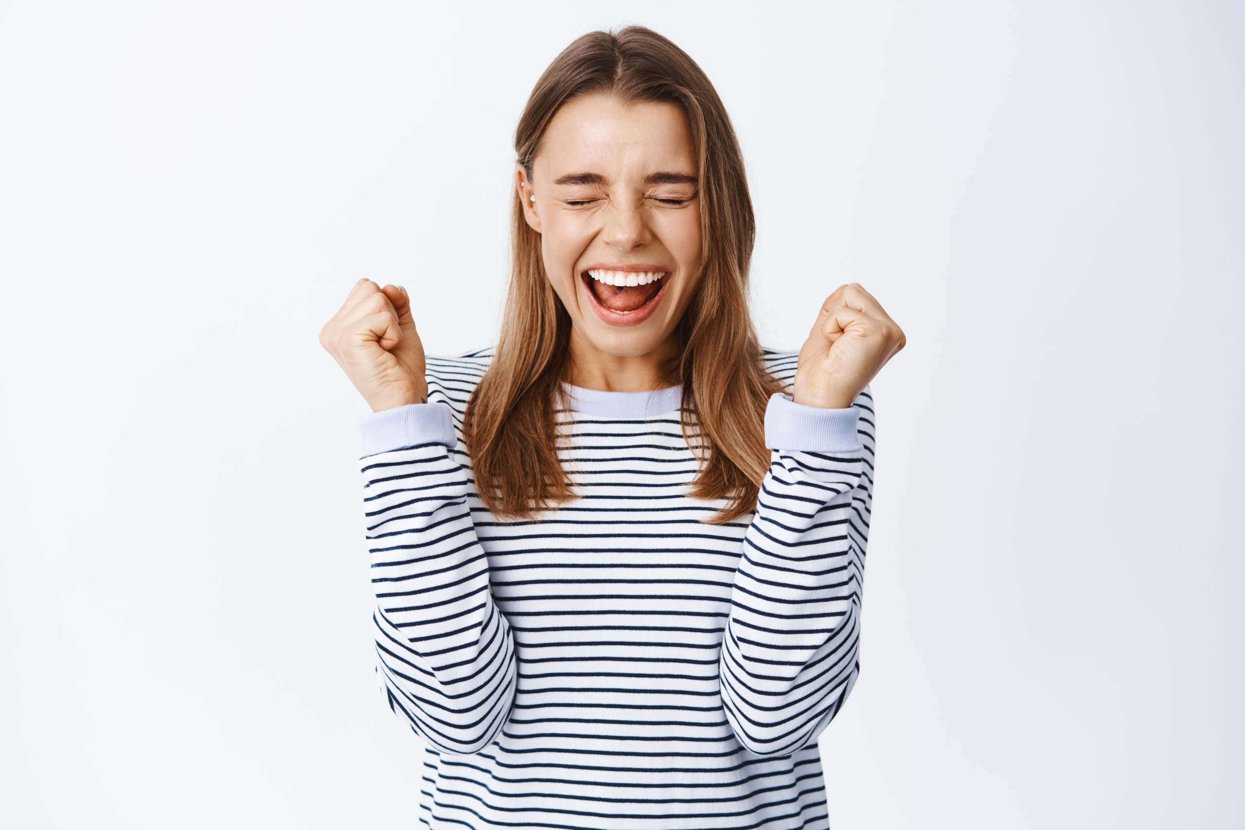 I did it, I am winner. Excited blond girl shouting with joy, jumping from happiness and celebrating win, smiling amazed, triumphing from success, white background
